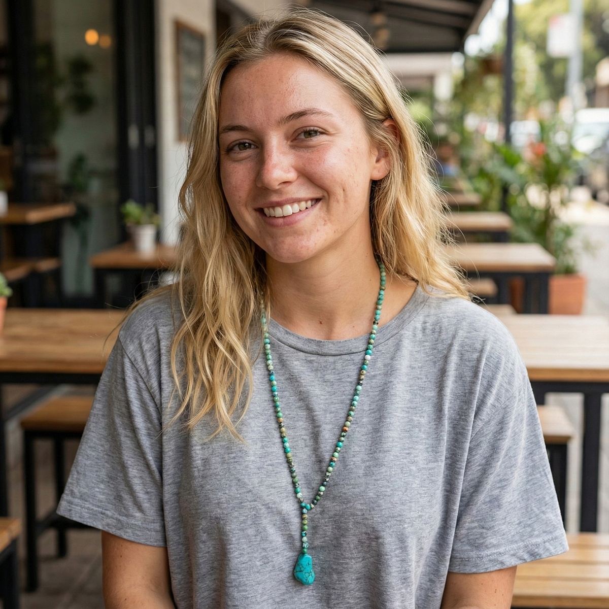 Woman with a beaded necklace smiling in an outdoor setting
