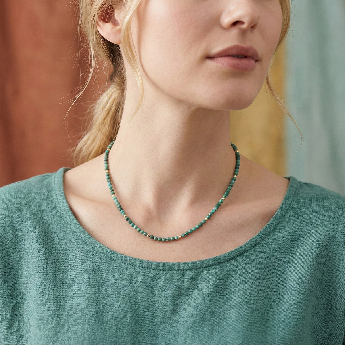 Woman wearing a green beaded necklace against a blurred background