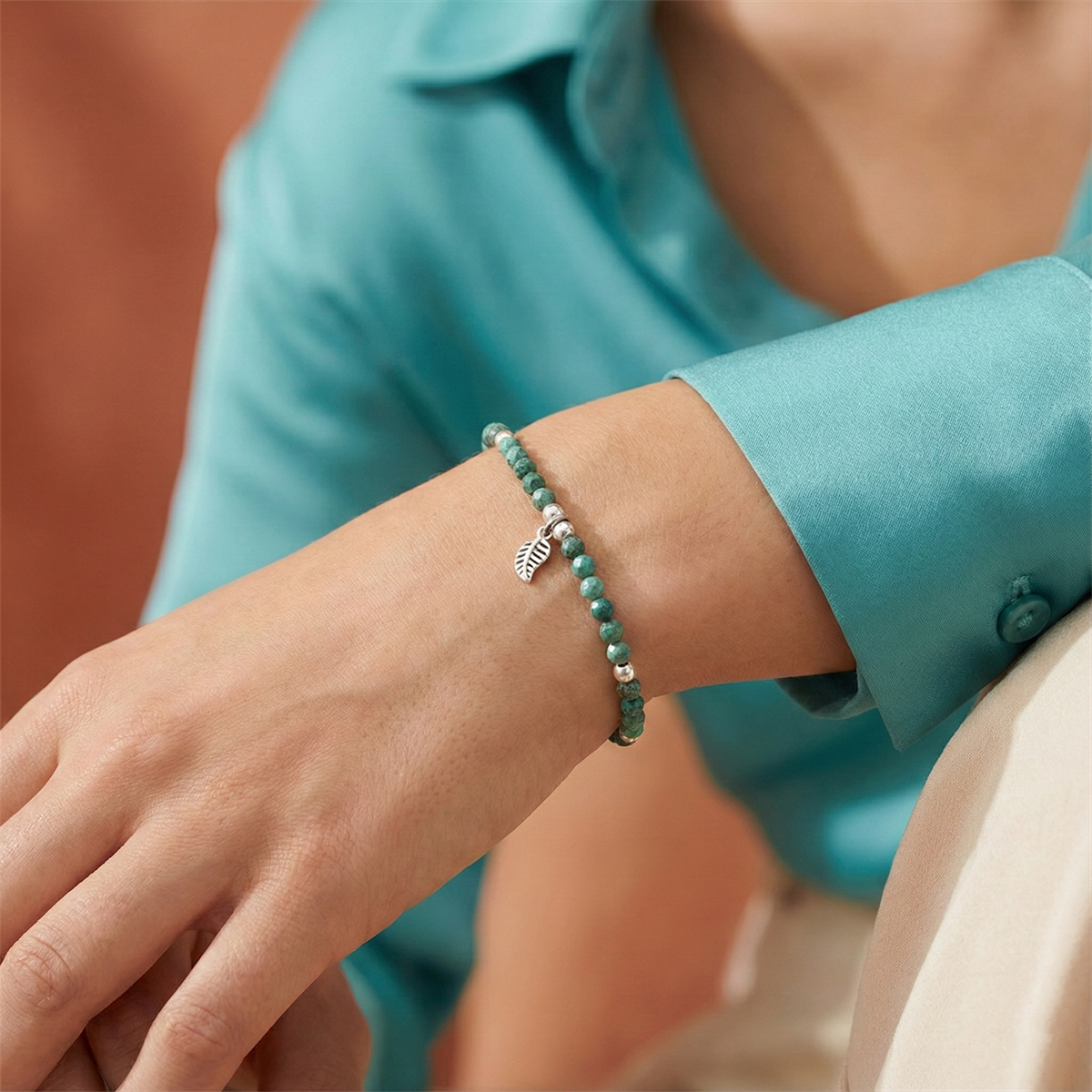 Person wearing a green beaded bracelet with a blurred background