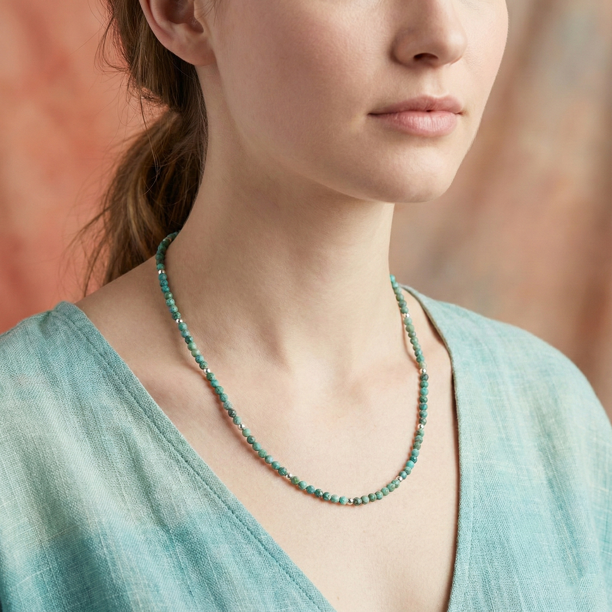 Woman wearing a green beaded necklace against a blurred background