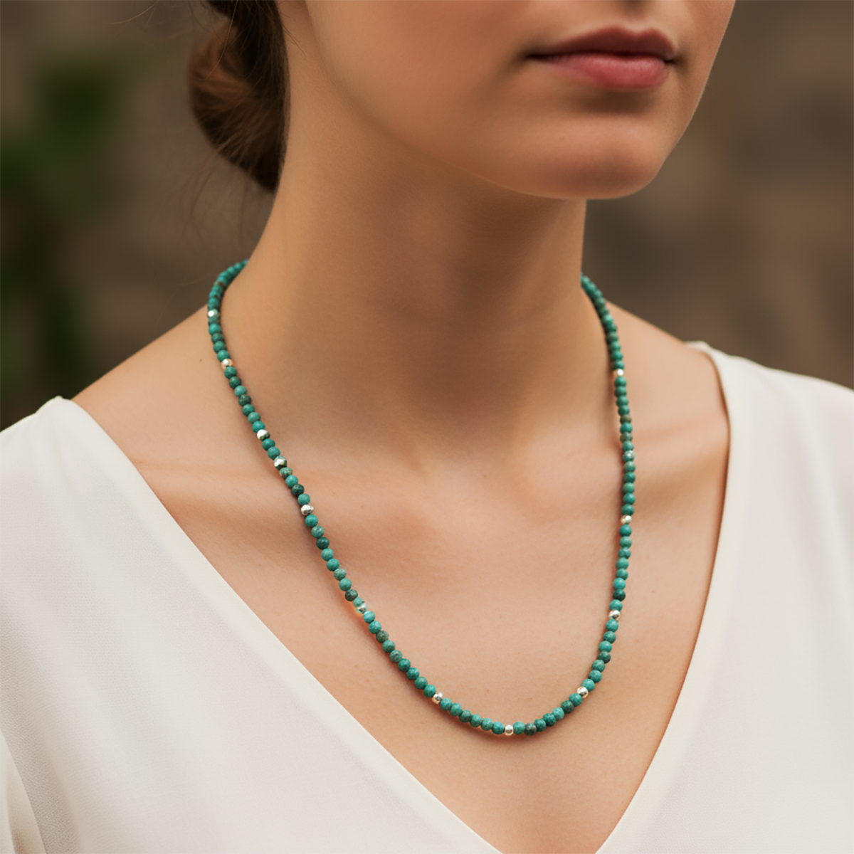 Woman wearing a green beaded necklace against a blurred background