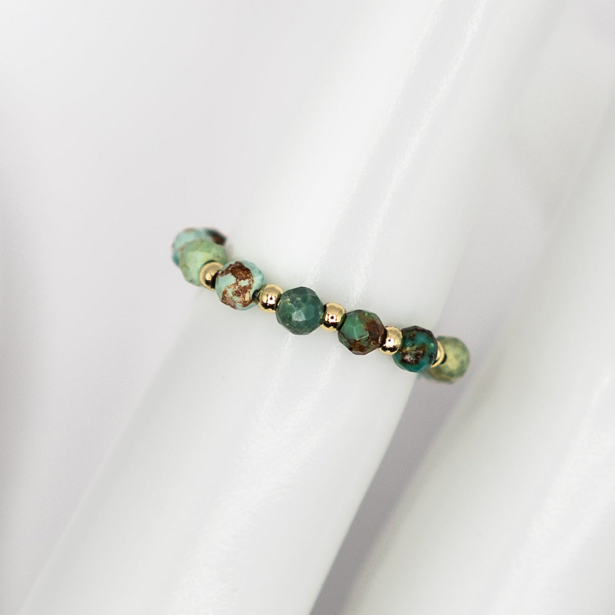 Beaded bracelet with green and gold beads on a white background