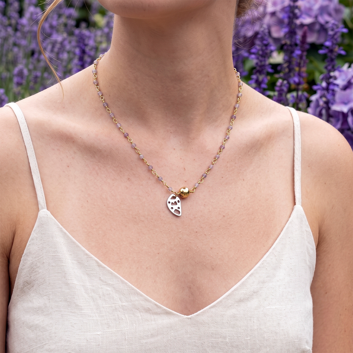 Necklace with a teardrop pendant worn by a person against a lavender background