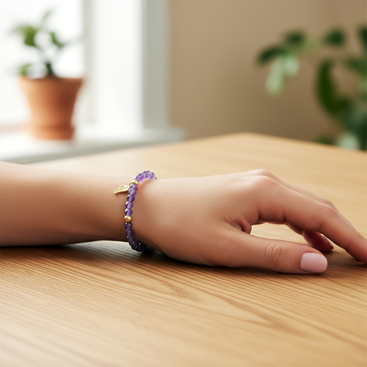 Hand wearing a purple beaded bracelet on a wooden surface with a blurred indoor background