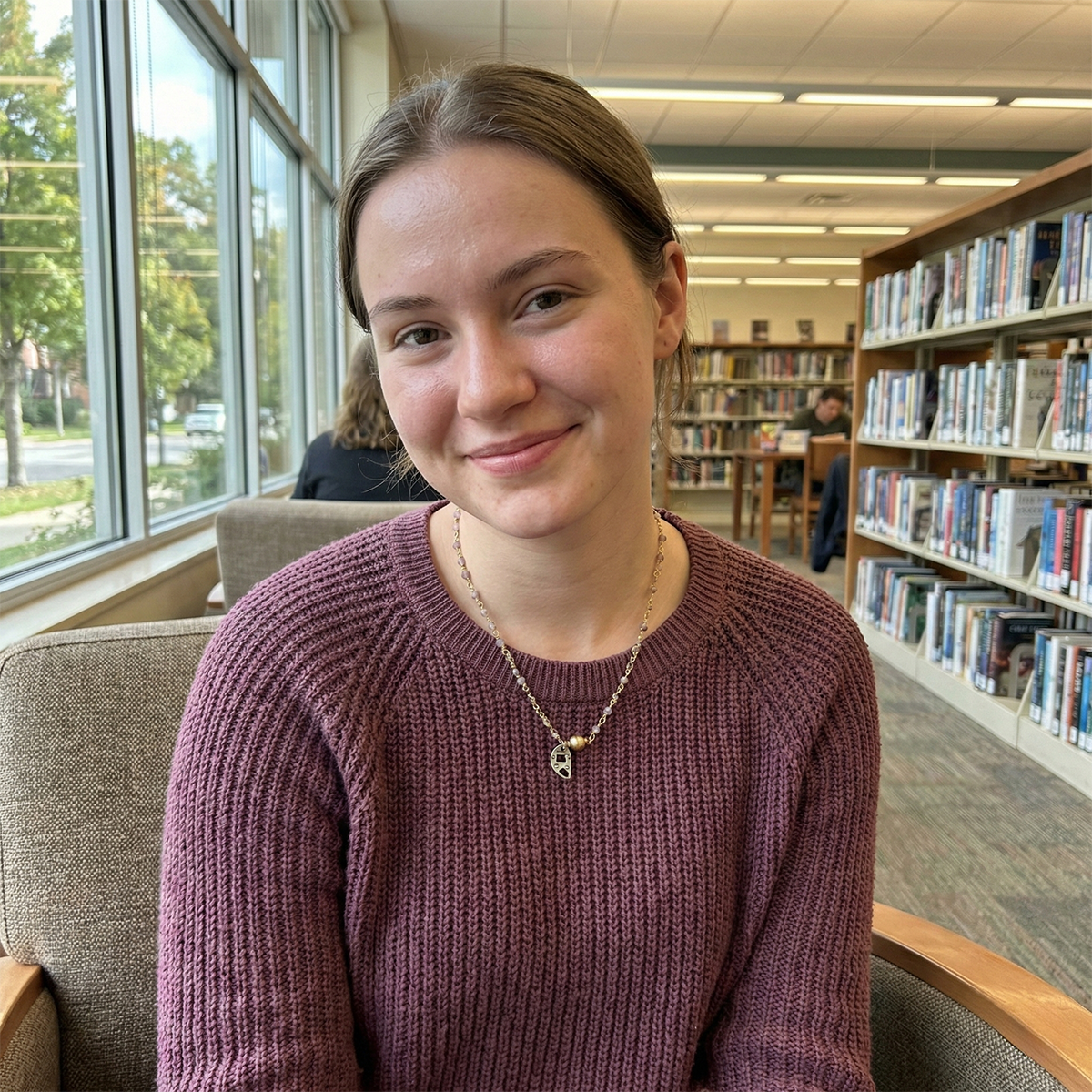 Young woman sitting in a library smiling at the camera