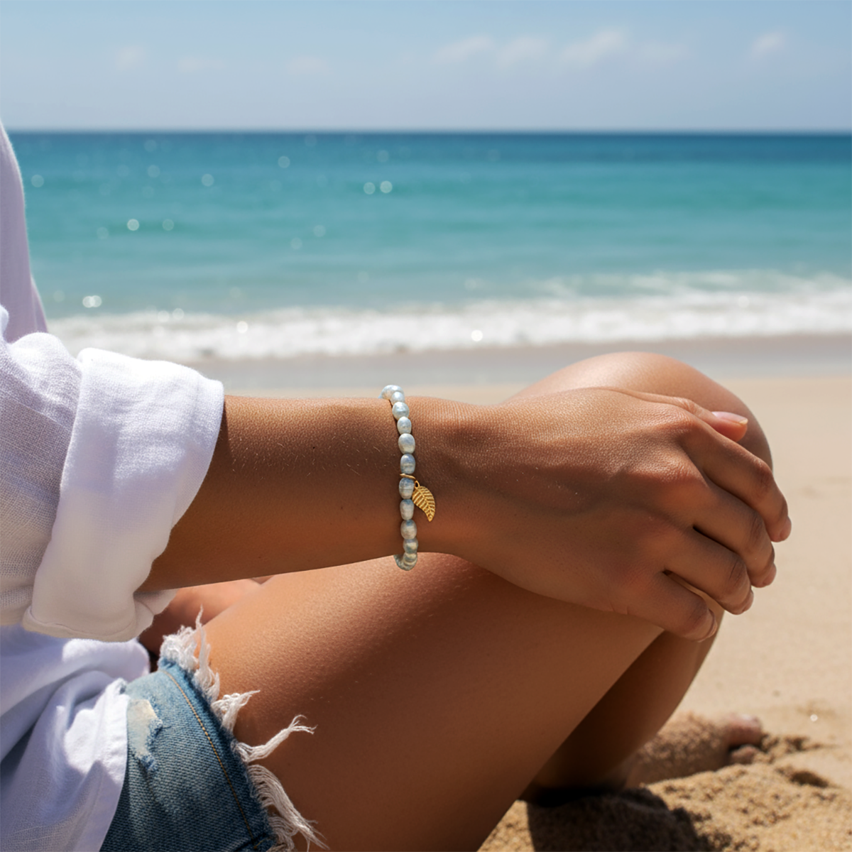 Person sitting on a beach with a clear blue sky and ocean in the background