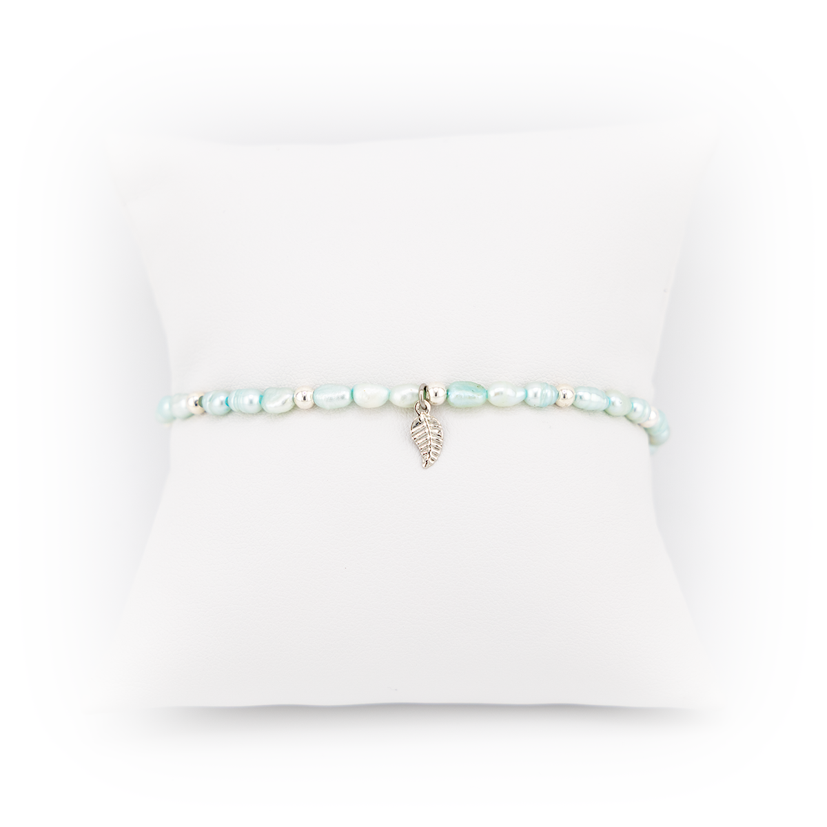 Pearl bracelet with a silver leaf charm on a white background