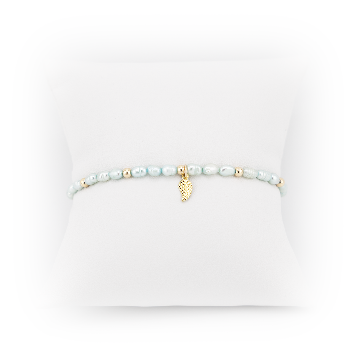 Pearl bracelet with a gold leaf charm on a white background