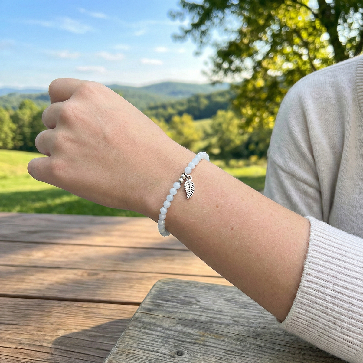 Person wearing a bracelet with a leaf charm outdoors