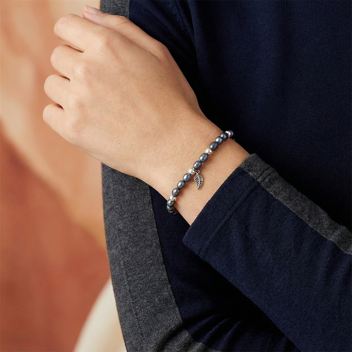 Person wearing a bracelet with a leaf charm on a blurred background