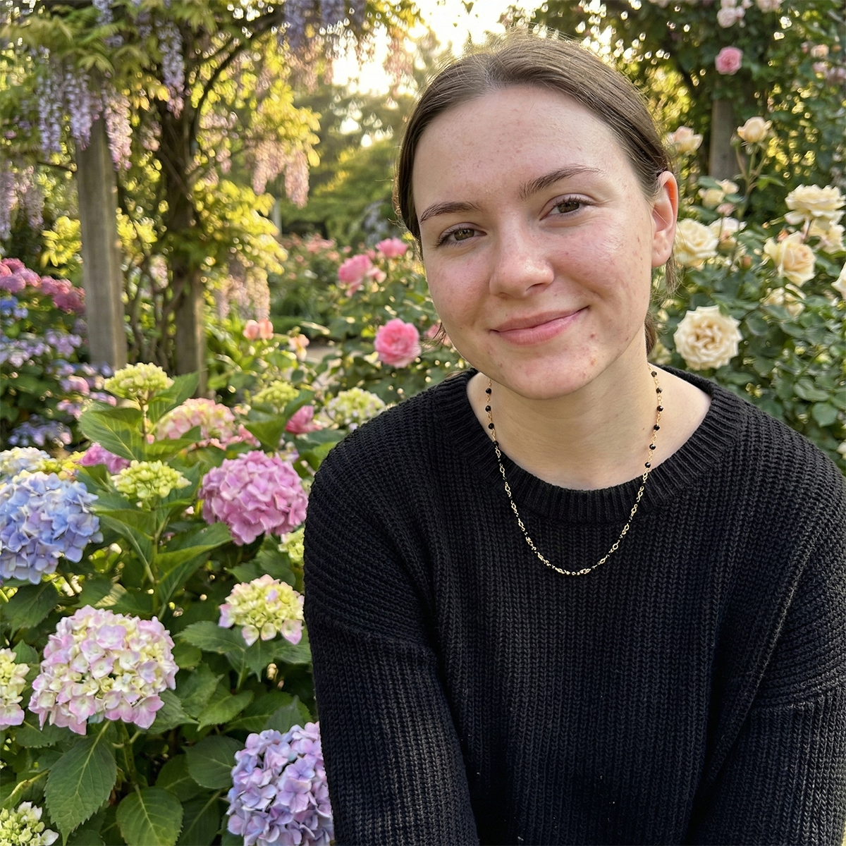 Woman standing in a garden with hydrangeas and other flowers