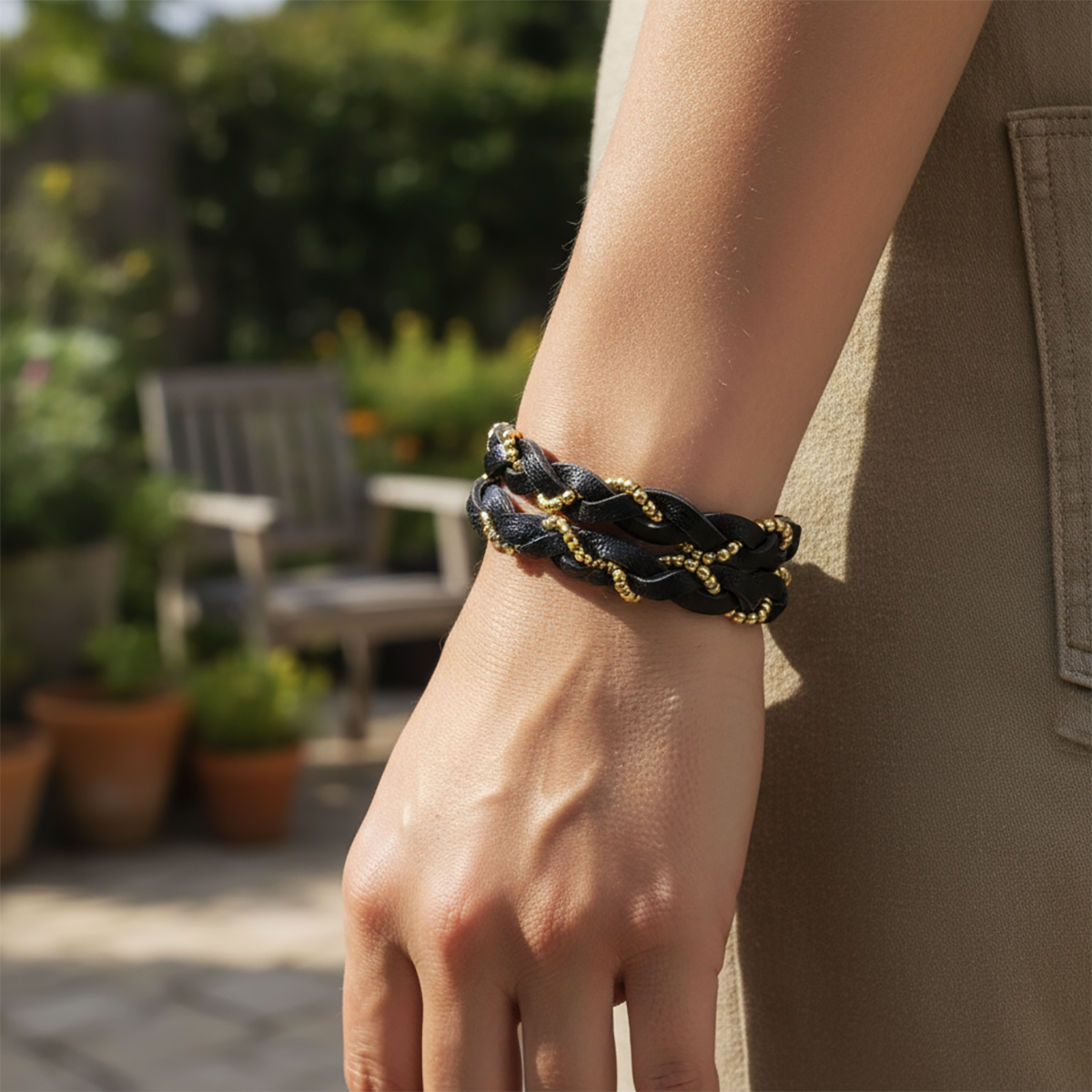 Person wearing a black and gold braided bracelet in an outdoor setting
