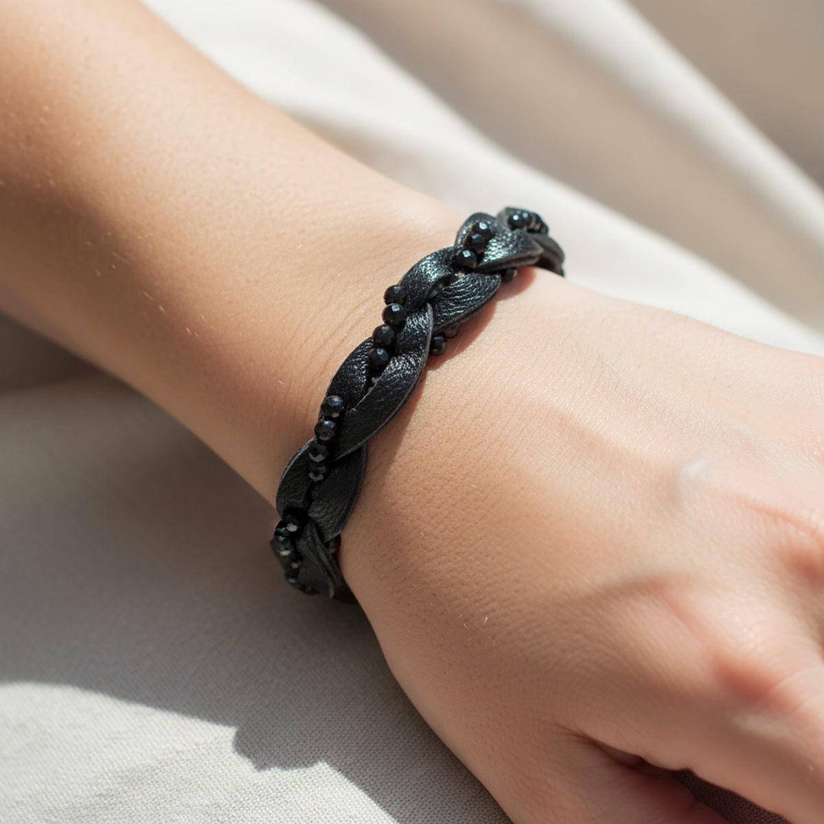 Black braided bracelet on a wrist with a neutral background