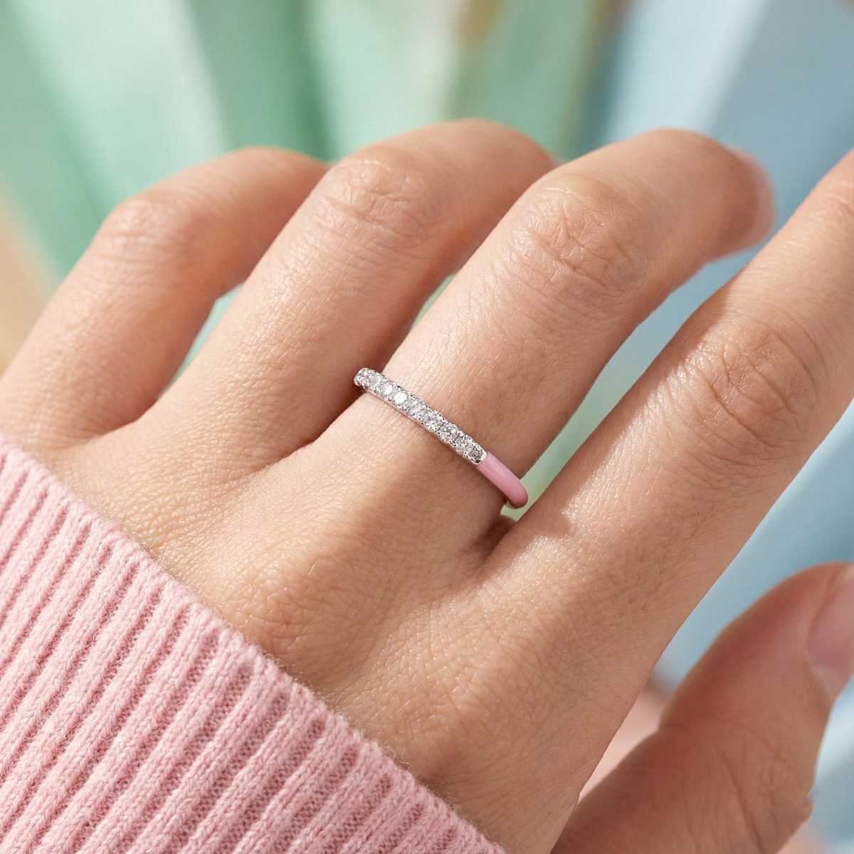 Close-up of a hand wearing a diamond ring with a blurred background