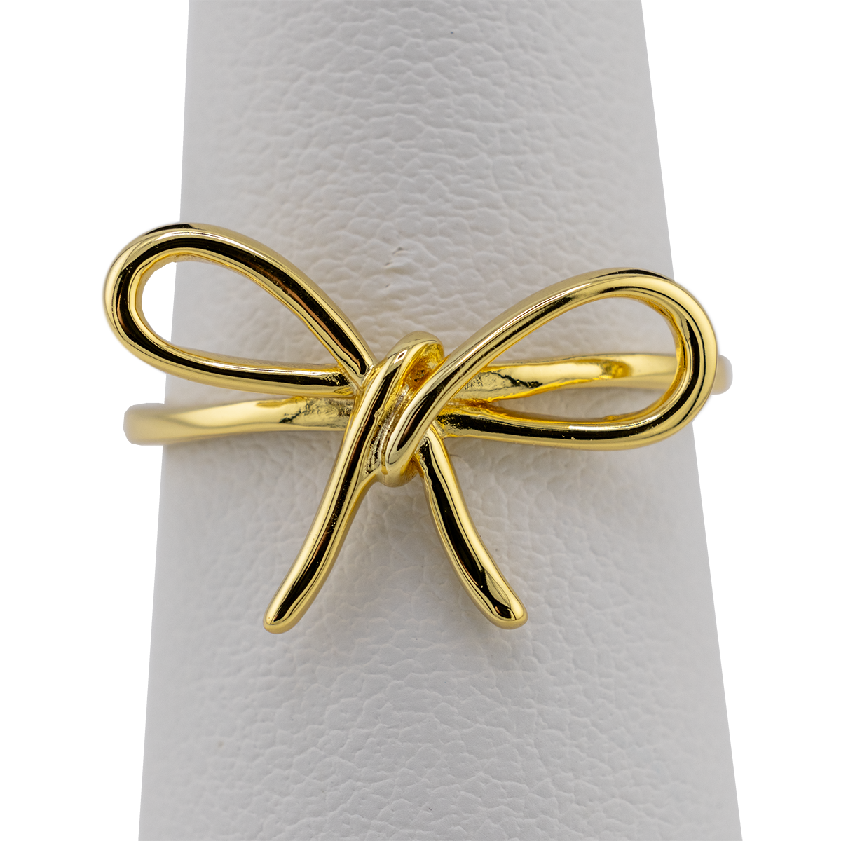 Gold bow-shaped ring on a white cushion