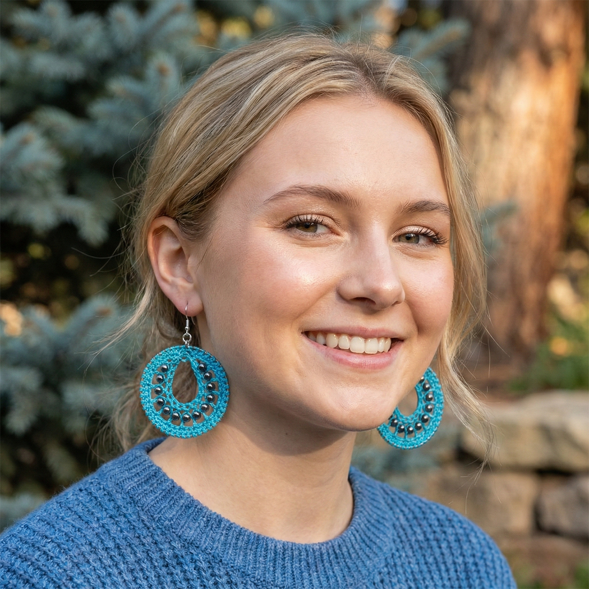 Woman wearing blue earrings with a blurred natural background