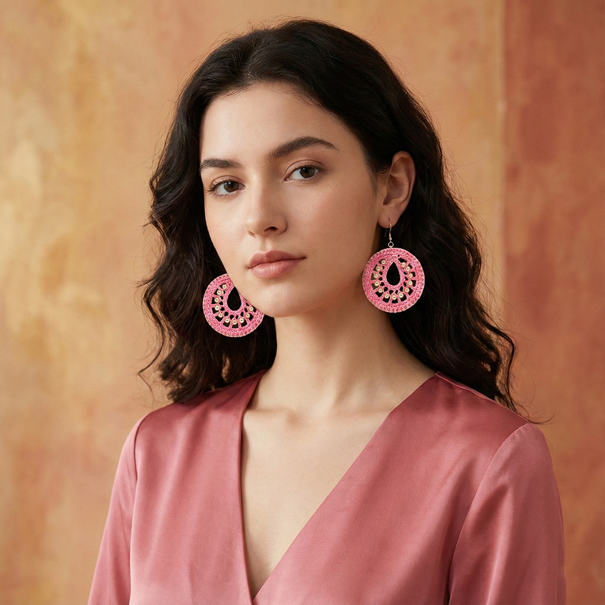 Woman wearing pink earrings against a warm-toned background