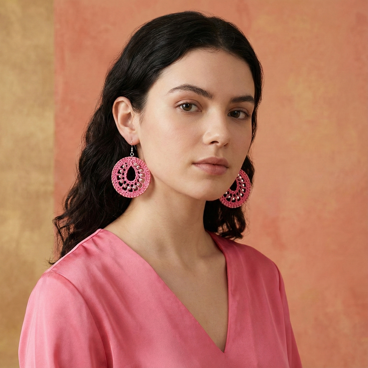 Woman wearing pink earrings against a warm-toned background
