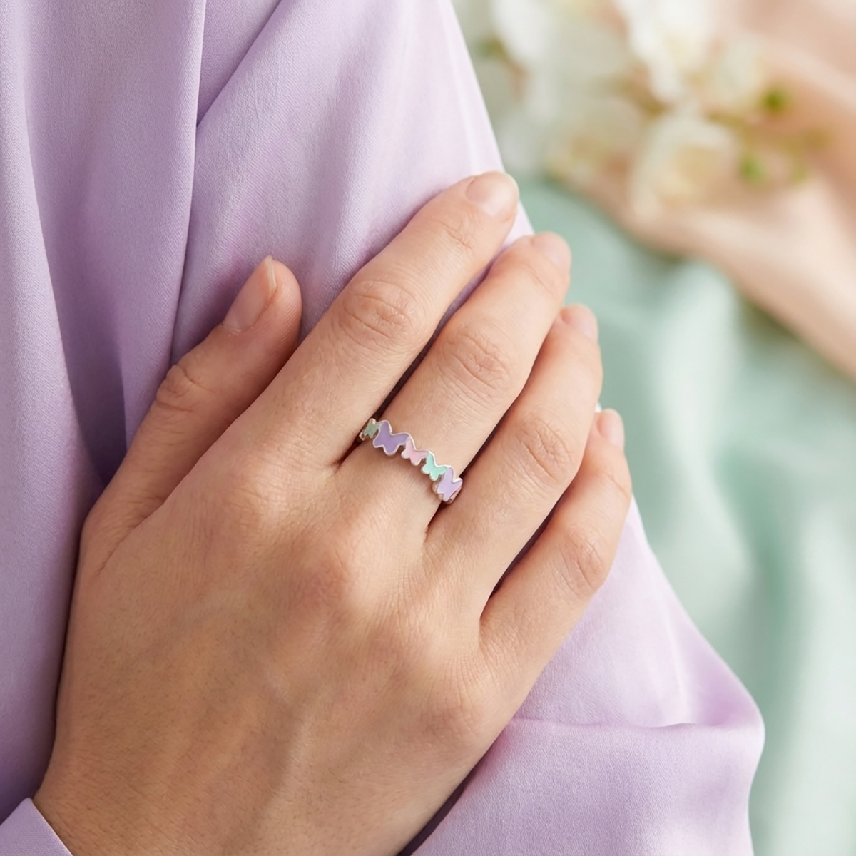 Hand wearing a colorful ring on a blurred background