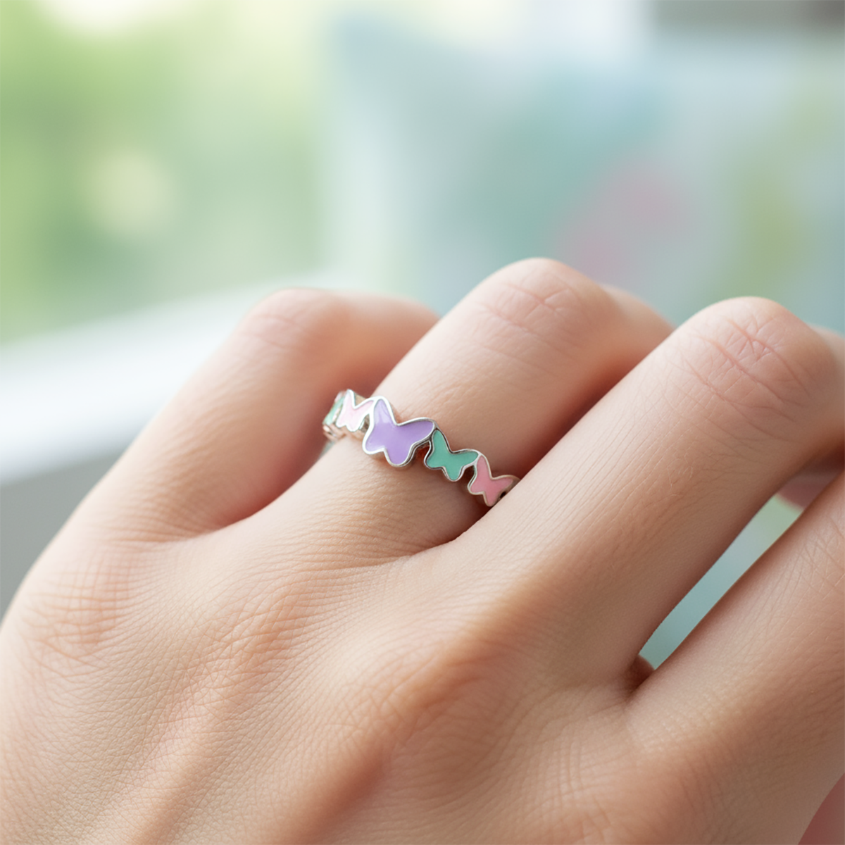 Hand wearing a colorful ring with a blurred background