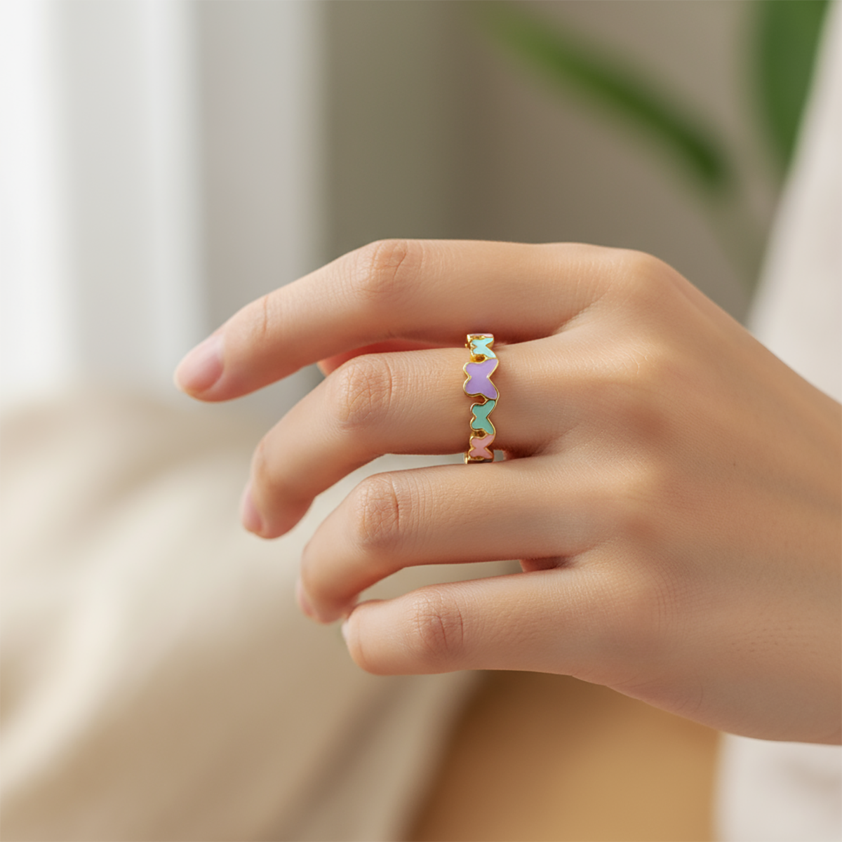 Hand wearing a colorful ring on a neutral background