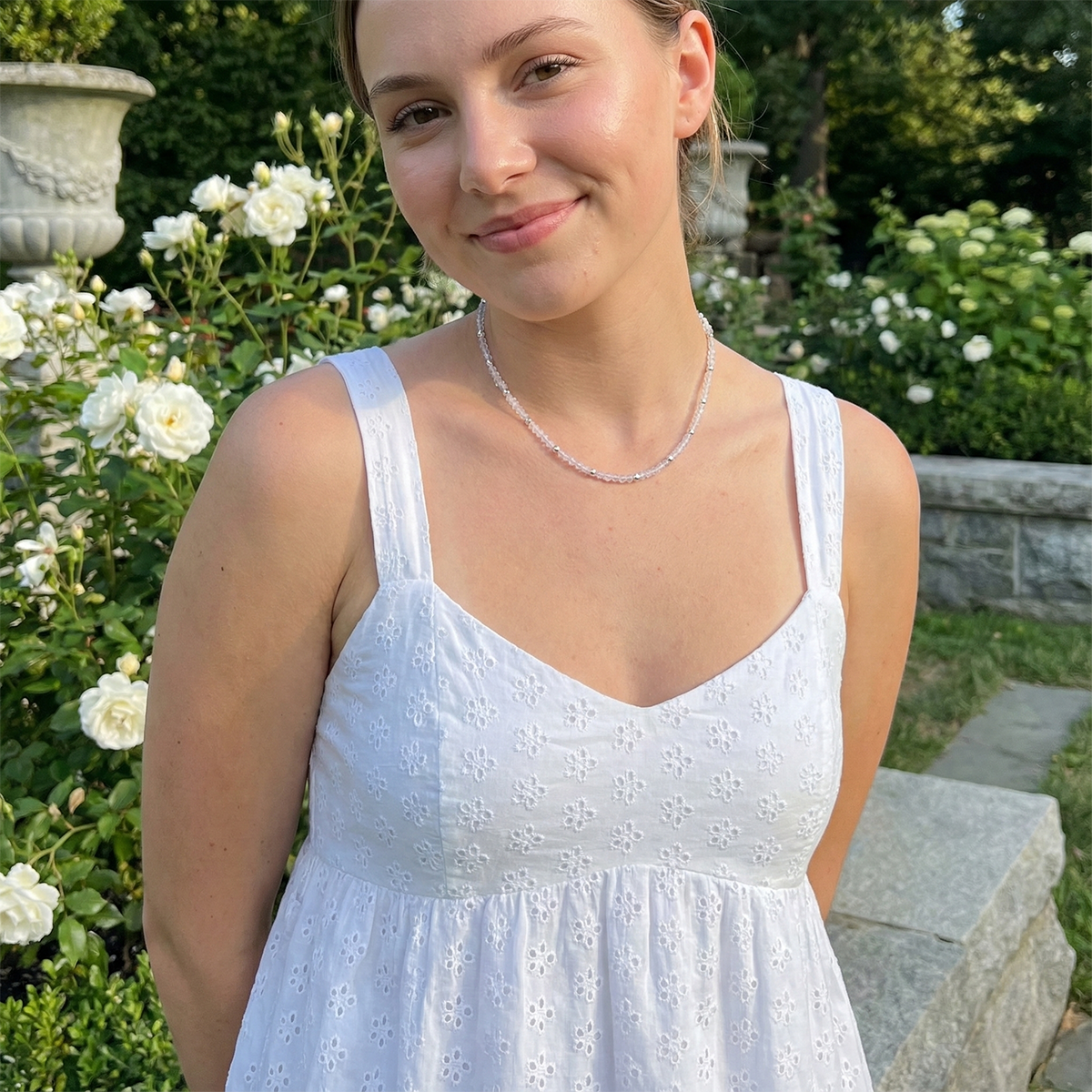 Woman in a white dress standing in a garden with white flowers