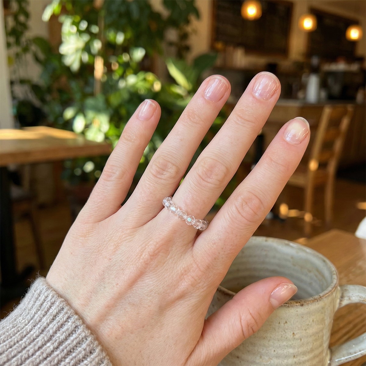 Hand wearing a ring with a blurred indoor background