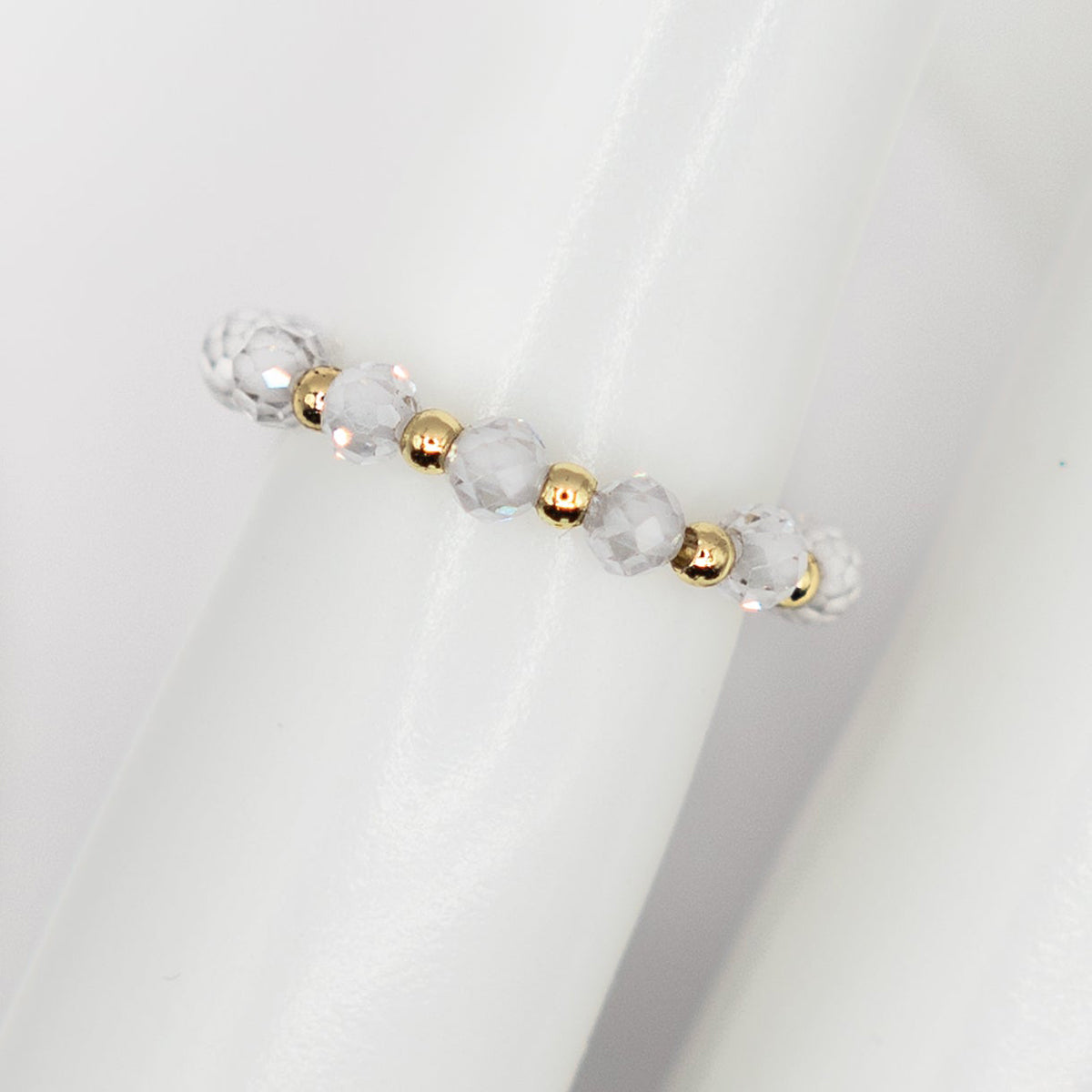 ring with clear beads and gold accents on a white background