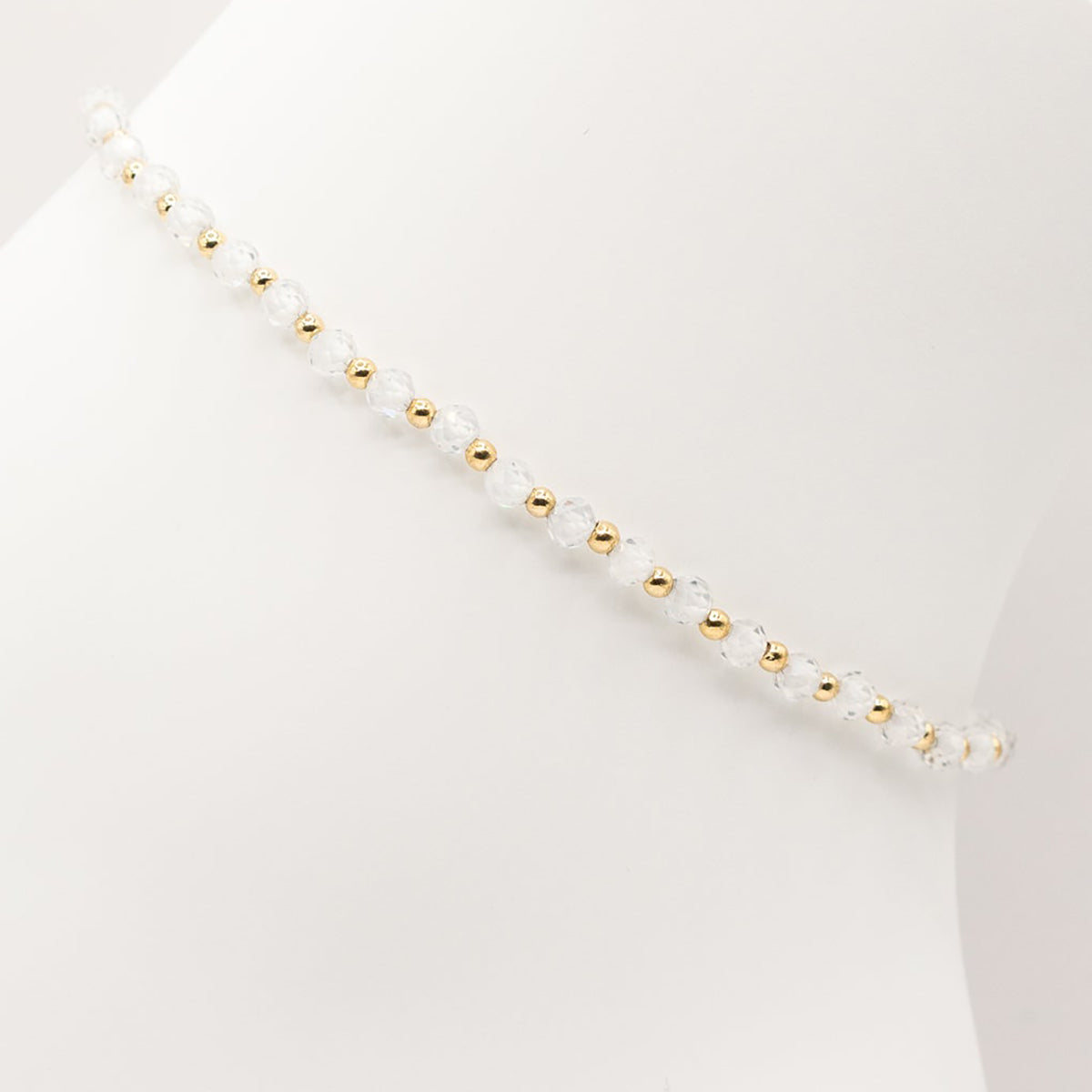 Necklace with alternating white and gold beads on a light gray background