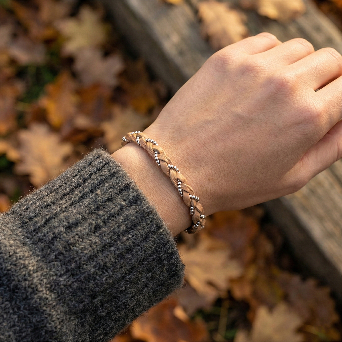 Hand wearing a braided bracelet with a blurred autumn background