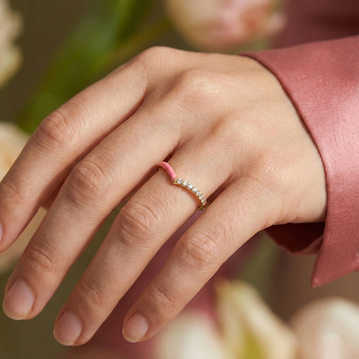 Hand wearing a ring with flowers in the background