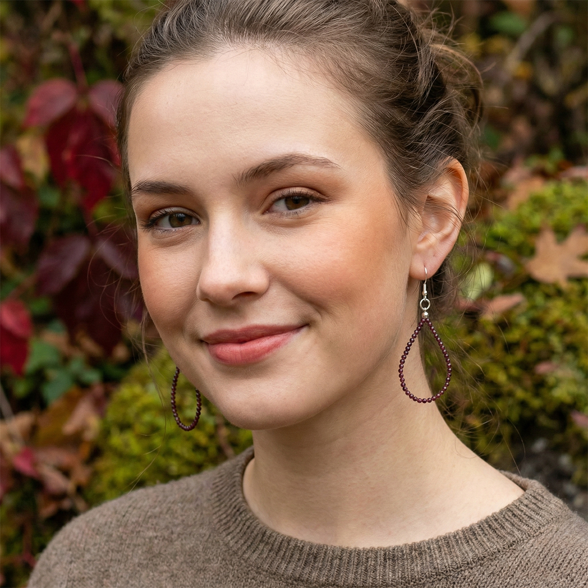 Woman wearing hoop earrings with a blurred natural background