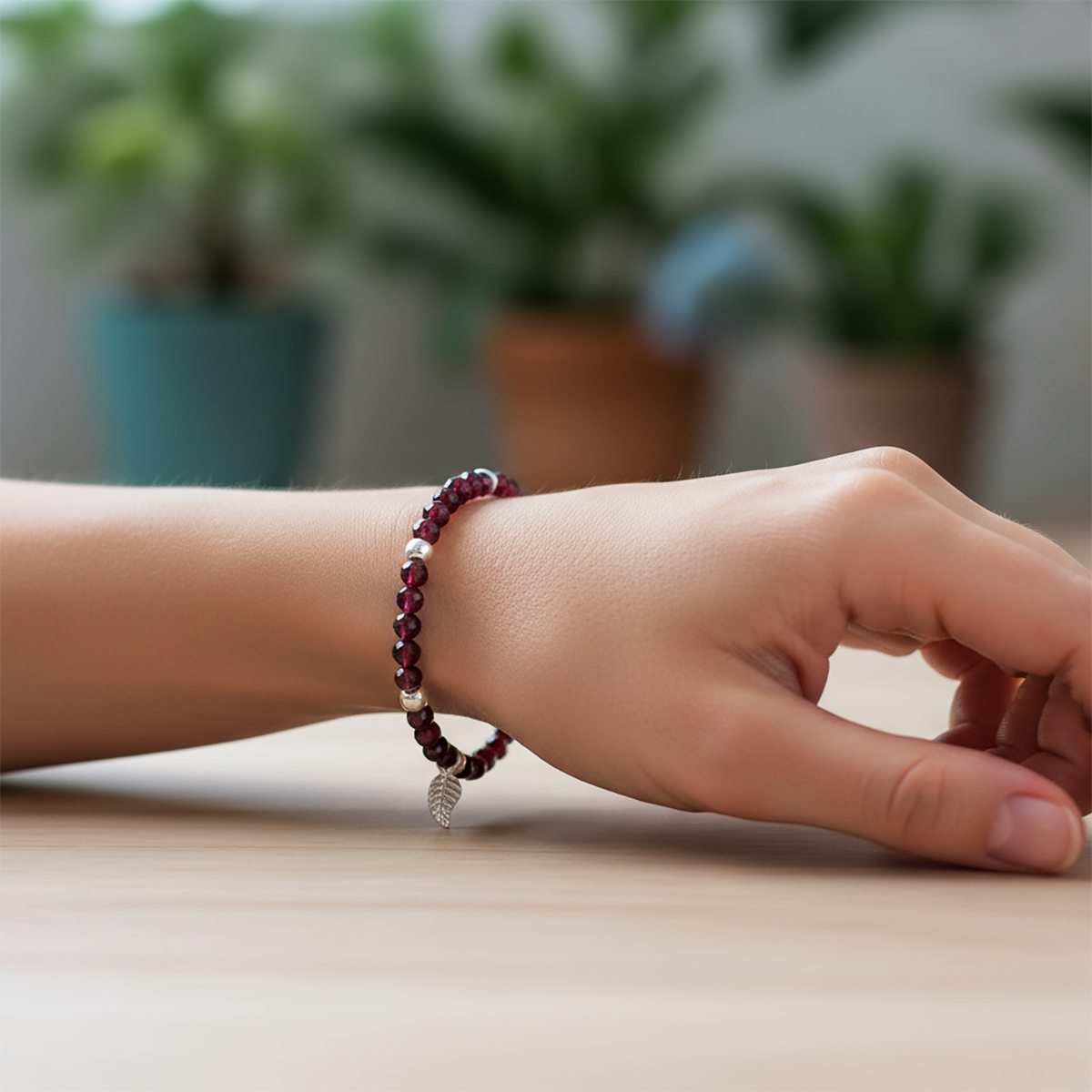 Hand wearing a beaded bracelet with a blurred indoor background