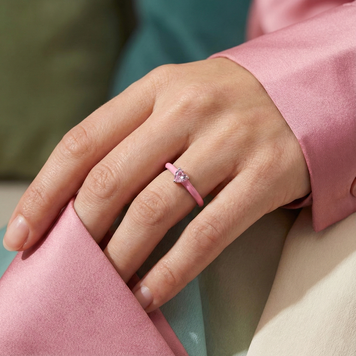 Hand wearing a pink ring with a blurred background