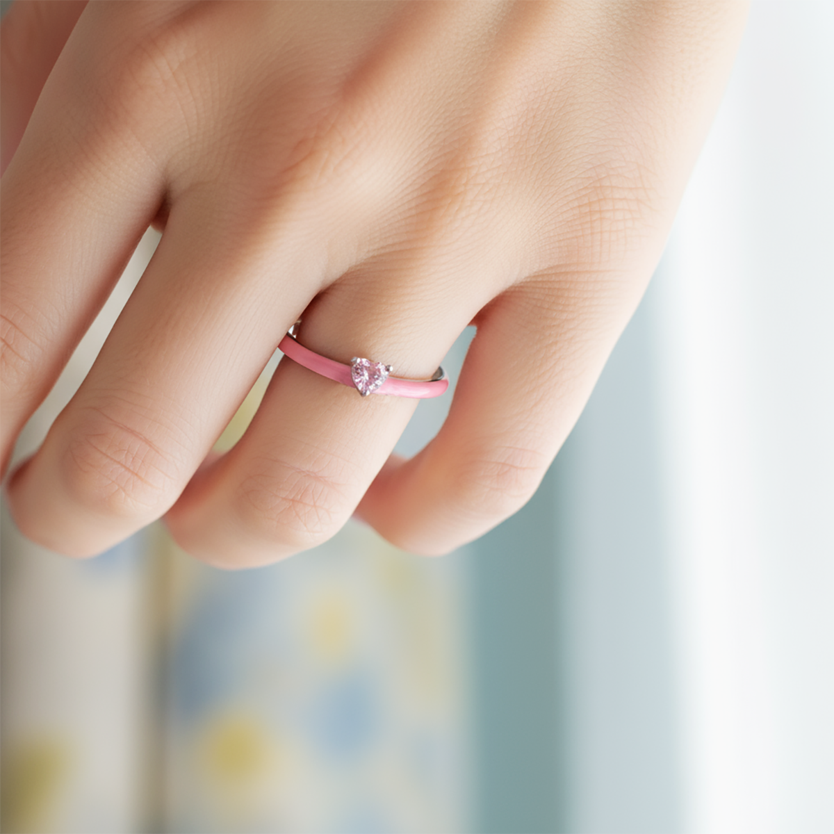 Close-up of a hand wearing a pink ring with a blurred background