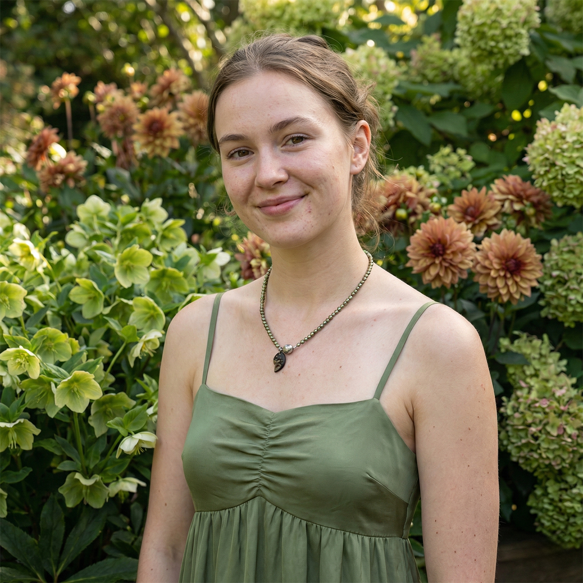 Woman in a green dress standing in front of flowers