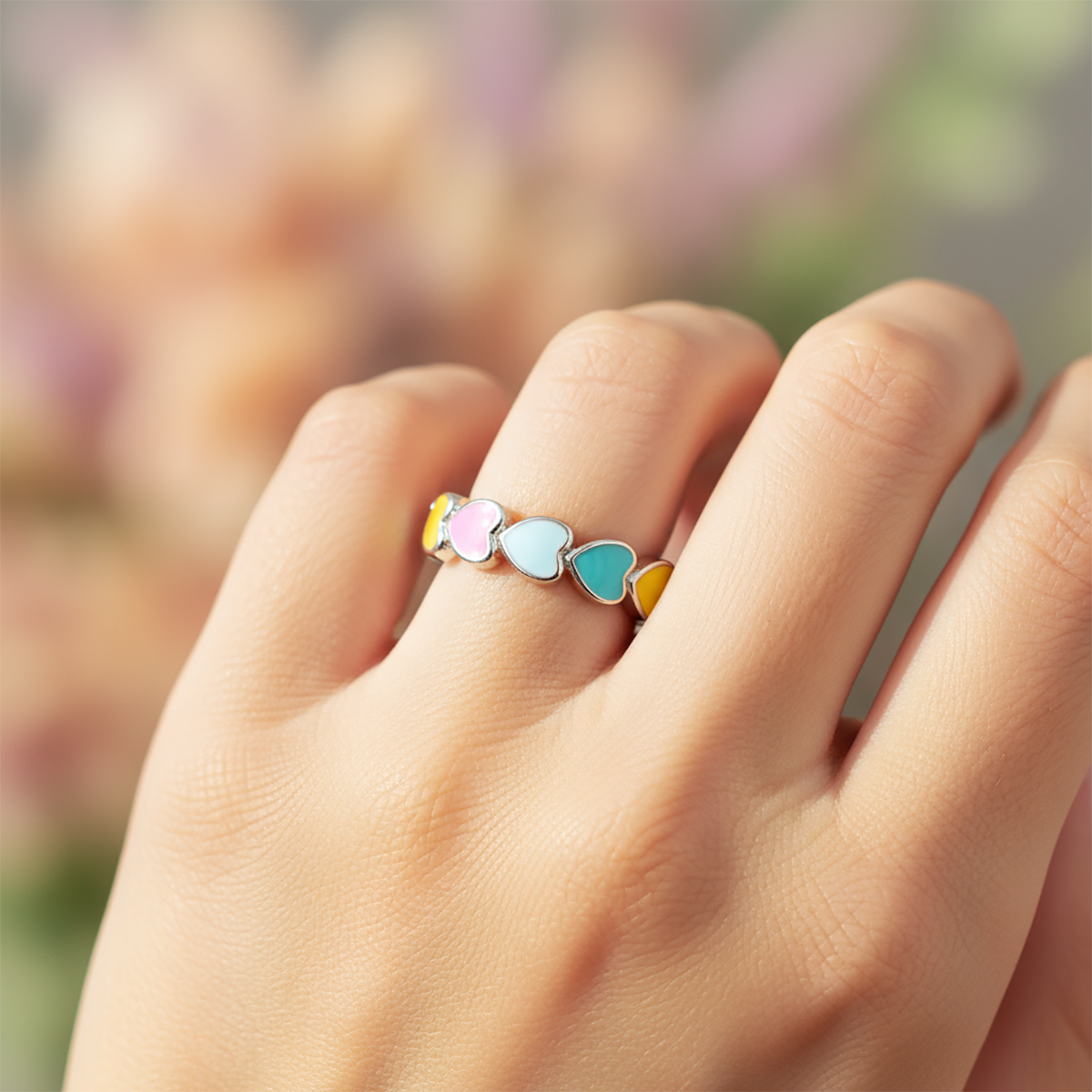Colorful heart-shaped ring on a hand with a blurred background