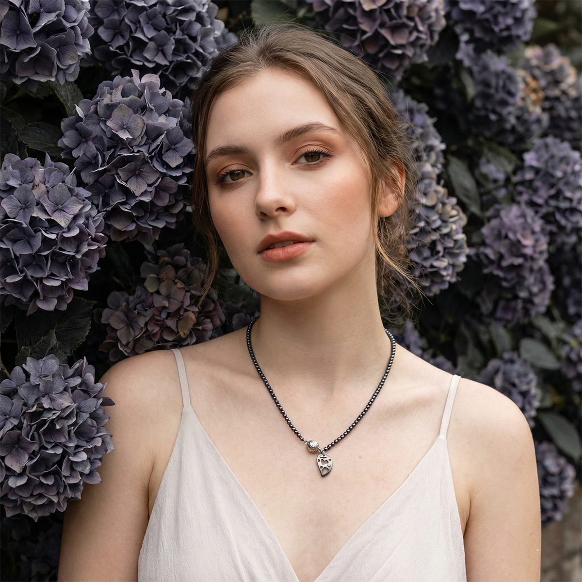 Woman wearing a necklace in front of purple flowers