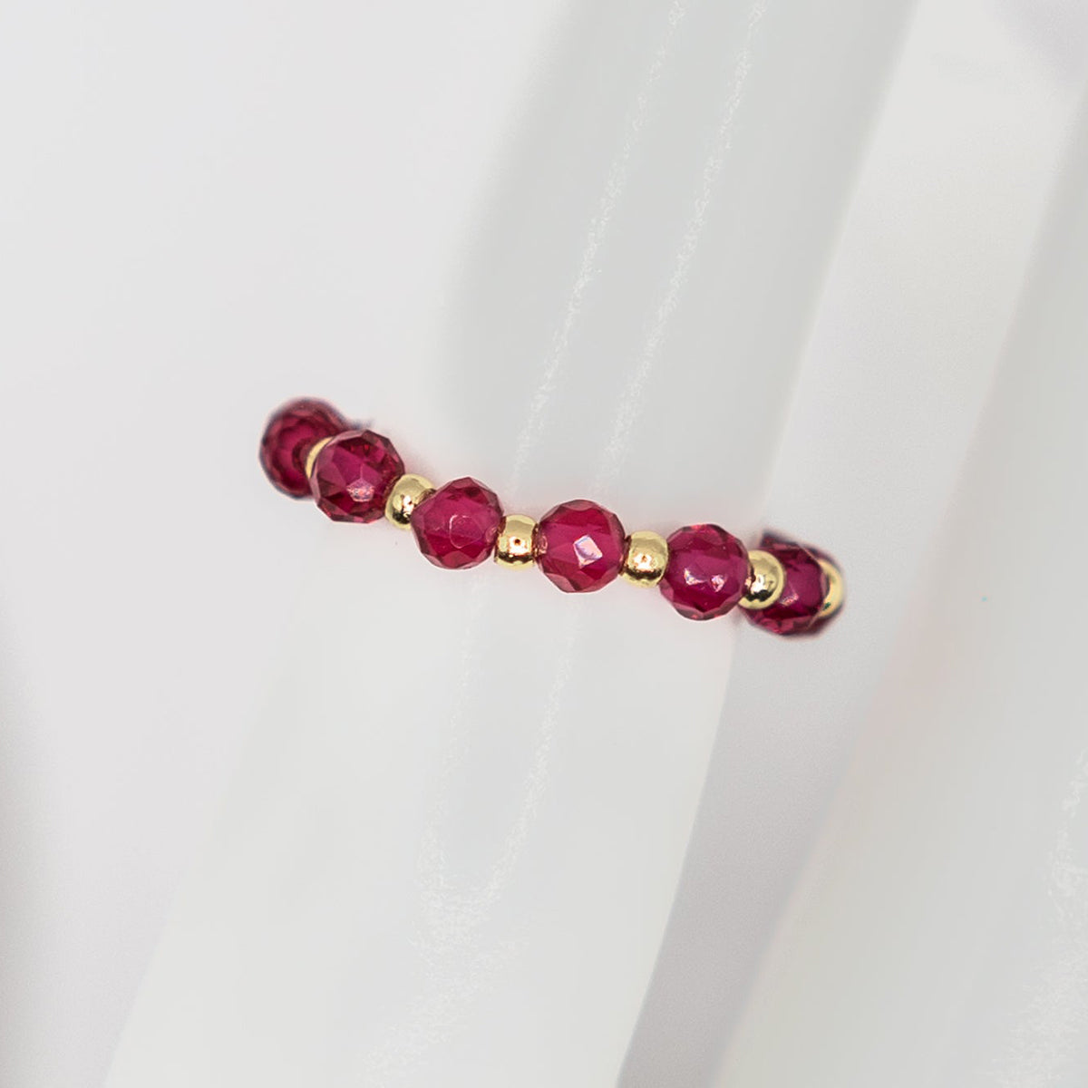 ring with red beads and gold accents on a white background