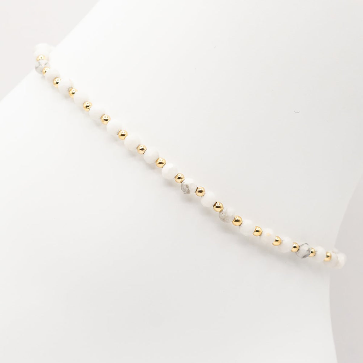 Necklace with alternating gold and pearl beads on a white background