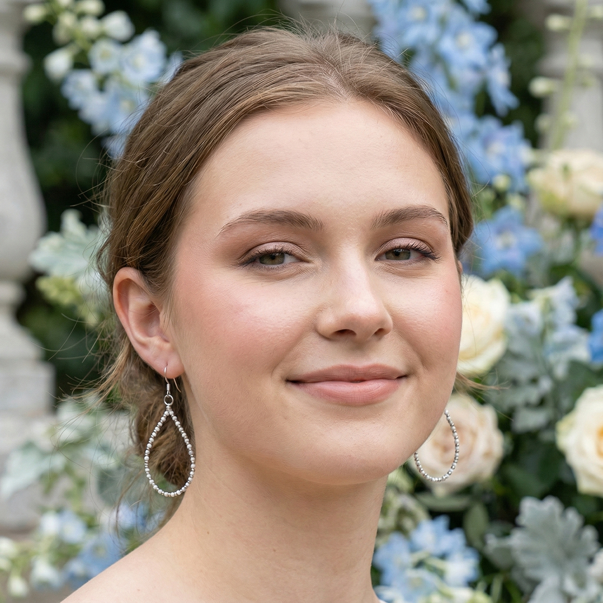 Woman with earrings standing in front of floral decorations