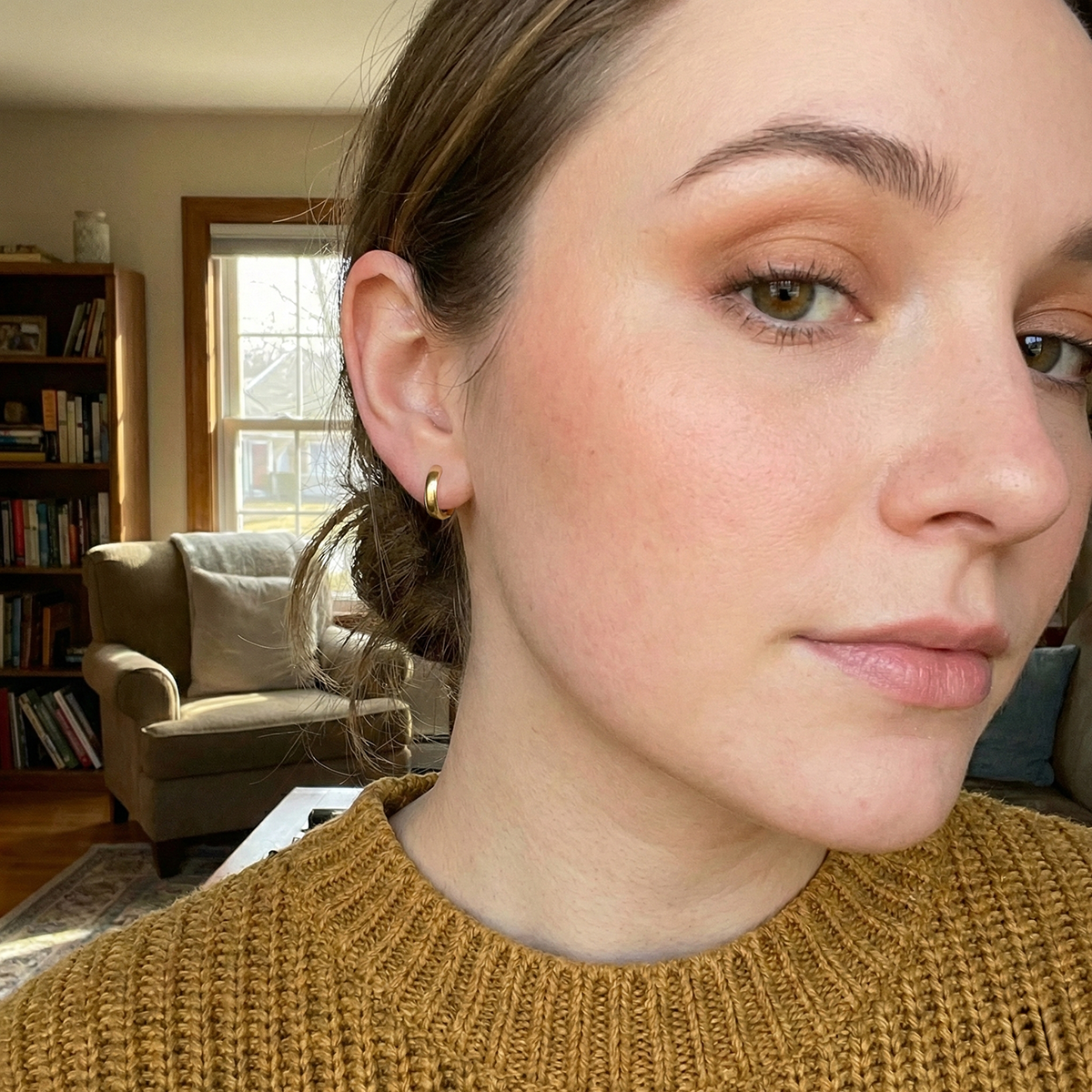 Close-up of a person wearing gold earrings in a living room setting