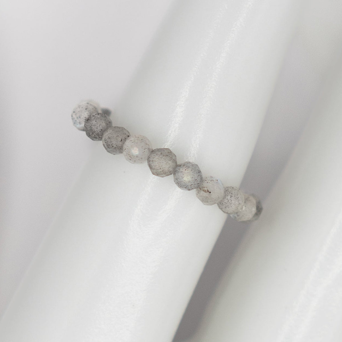 Beaded ring with gray and white stones on a white background