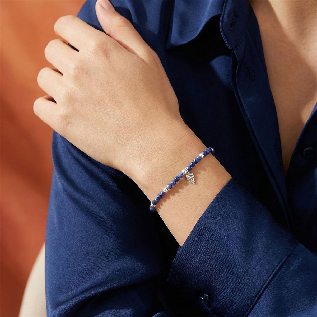 Person wearing a blue beaded bracelet on a dark blue background