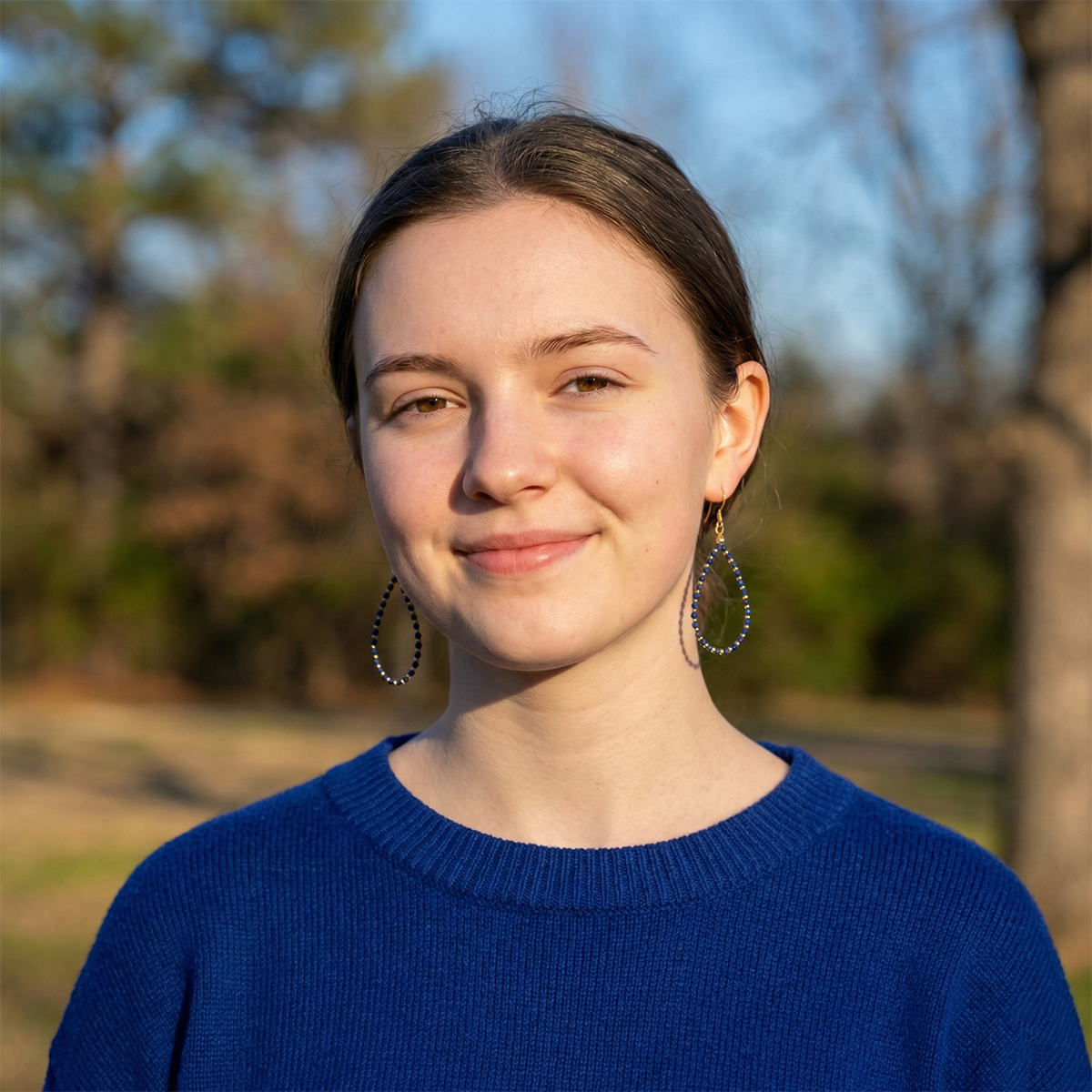 Woman wearing a blue sweater with a blurred natural background