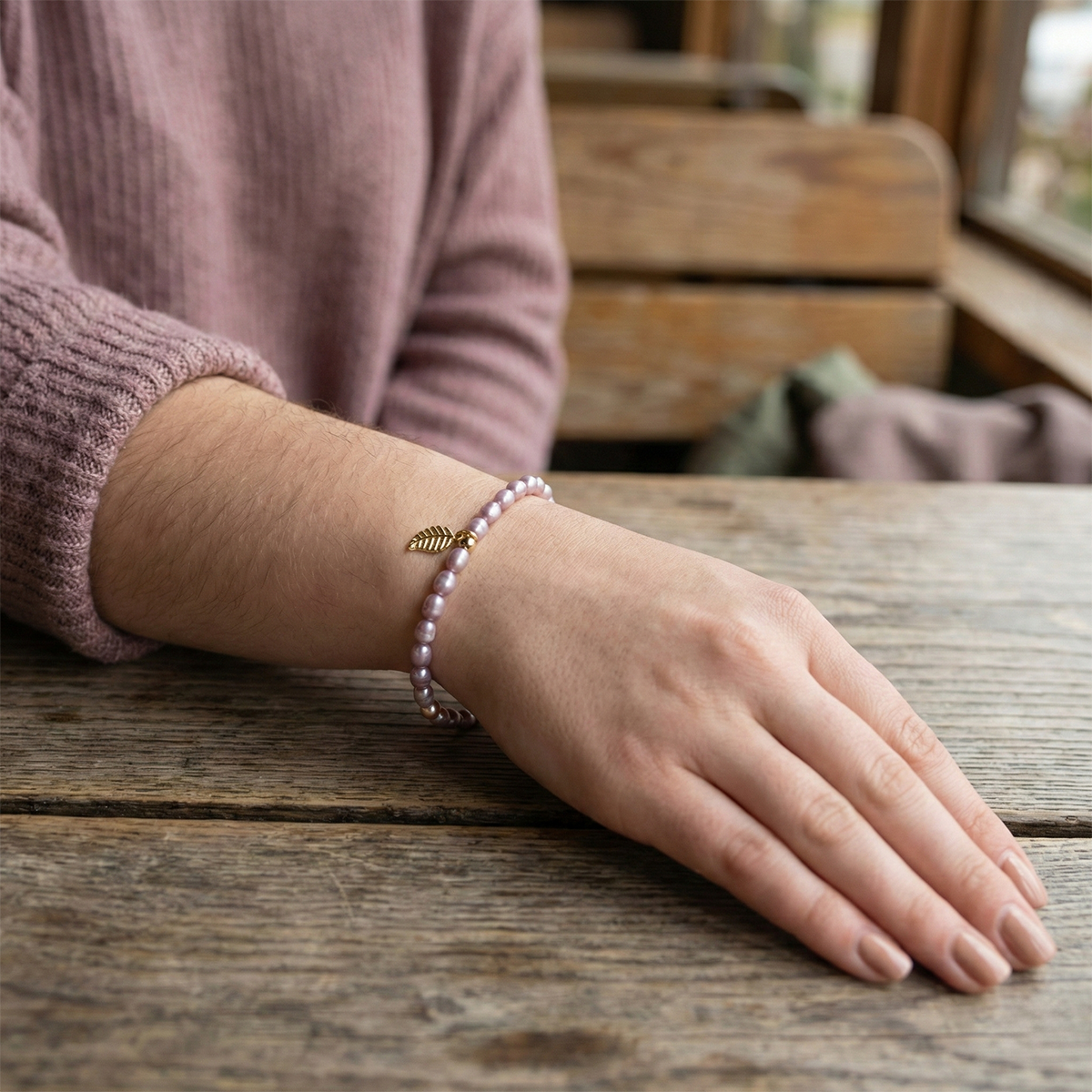 Hand wearing a bracelet on a wooden surface with a blurred background