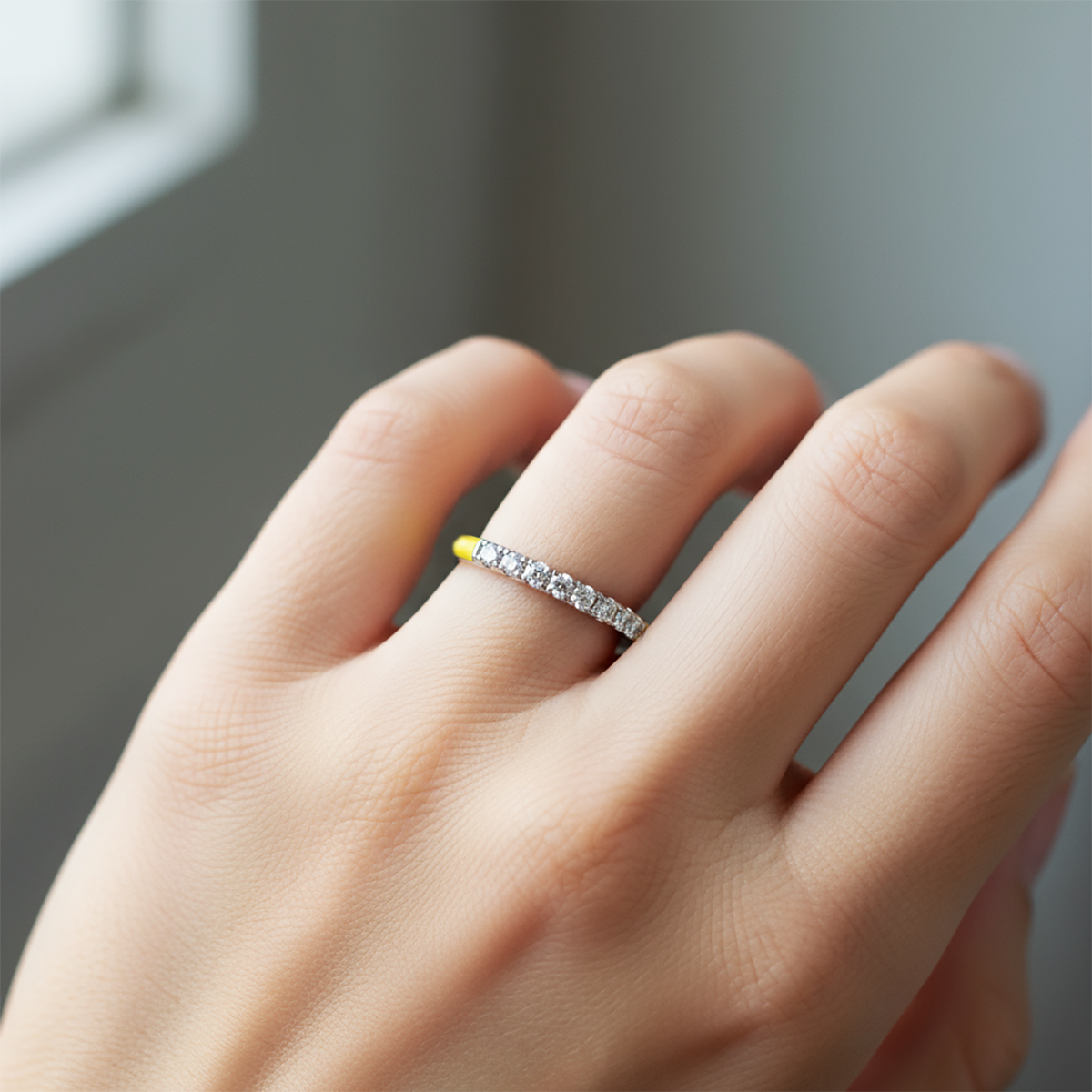Close-up of a hand wearing a diamond ring with a blurred background