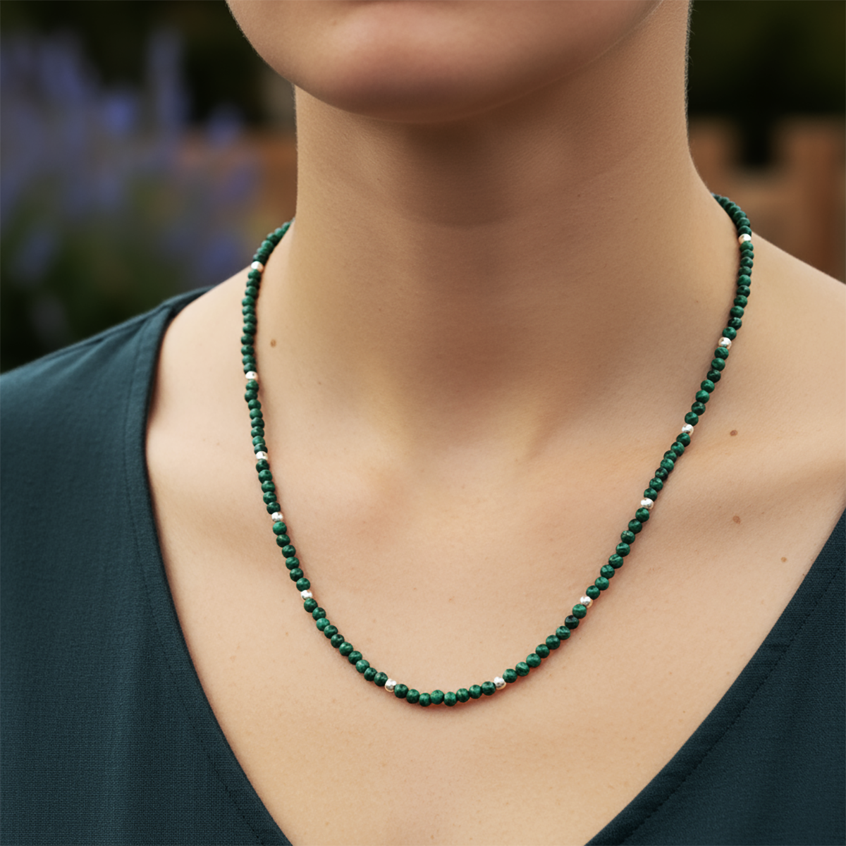 Green beaded necklace worn by a person with a blurred natural background