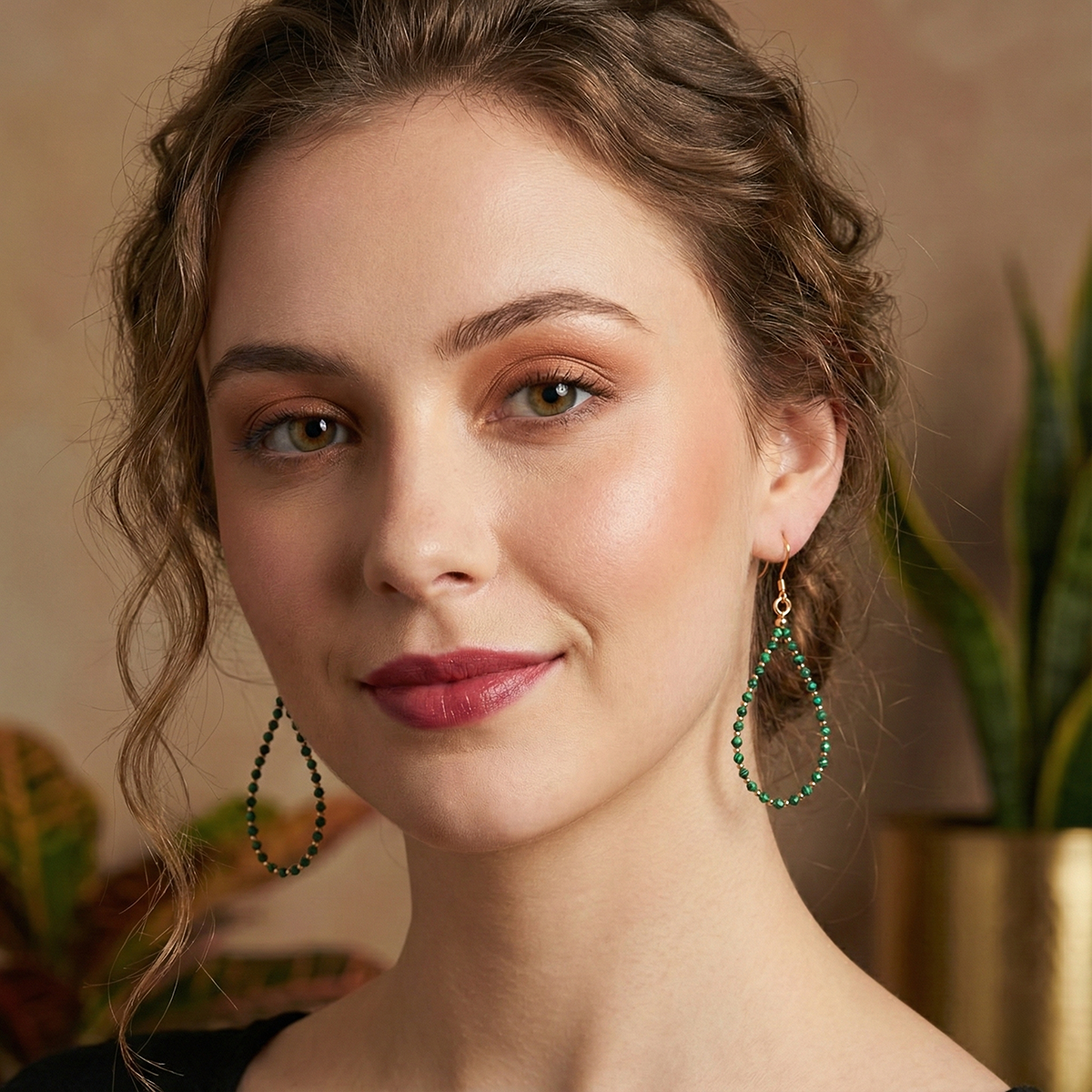 Woman wearing green hoop earrings with a blurred indoor background