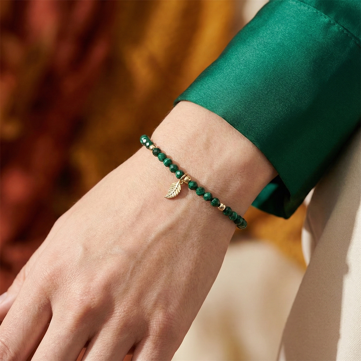 Close-up of a wrist wearing two green beaded bracelets with a blurred background